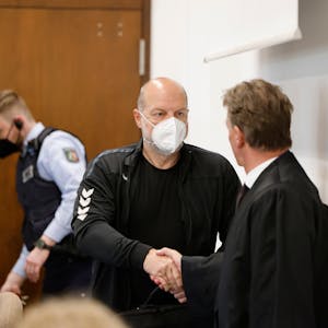 Der Angeklagte Thomas Drach begrüßt seinen Anwalt Andreas Kerkhof im Gerichtssaal des Landgerichts Köln.&nbsp;