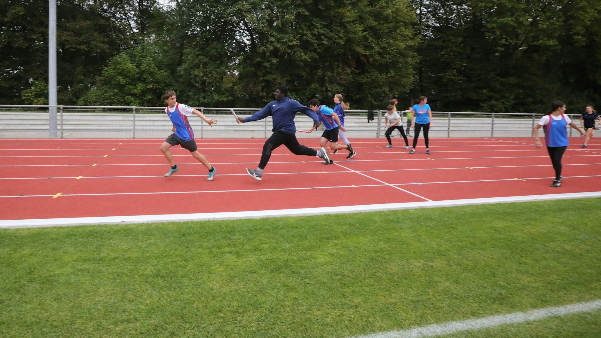 Staffellauf der GSV Leichtathleten zur Einweihung des neuen Sportplatzes. Auf dem Bild übergibt ein Läufer den Staffelstab an seinen Vordermann.