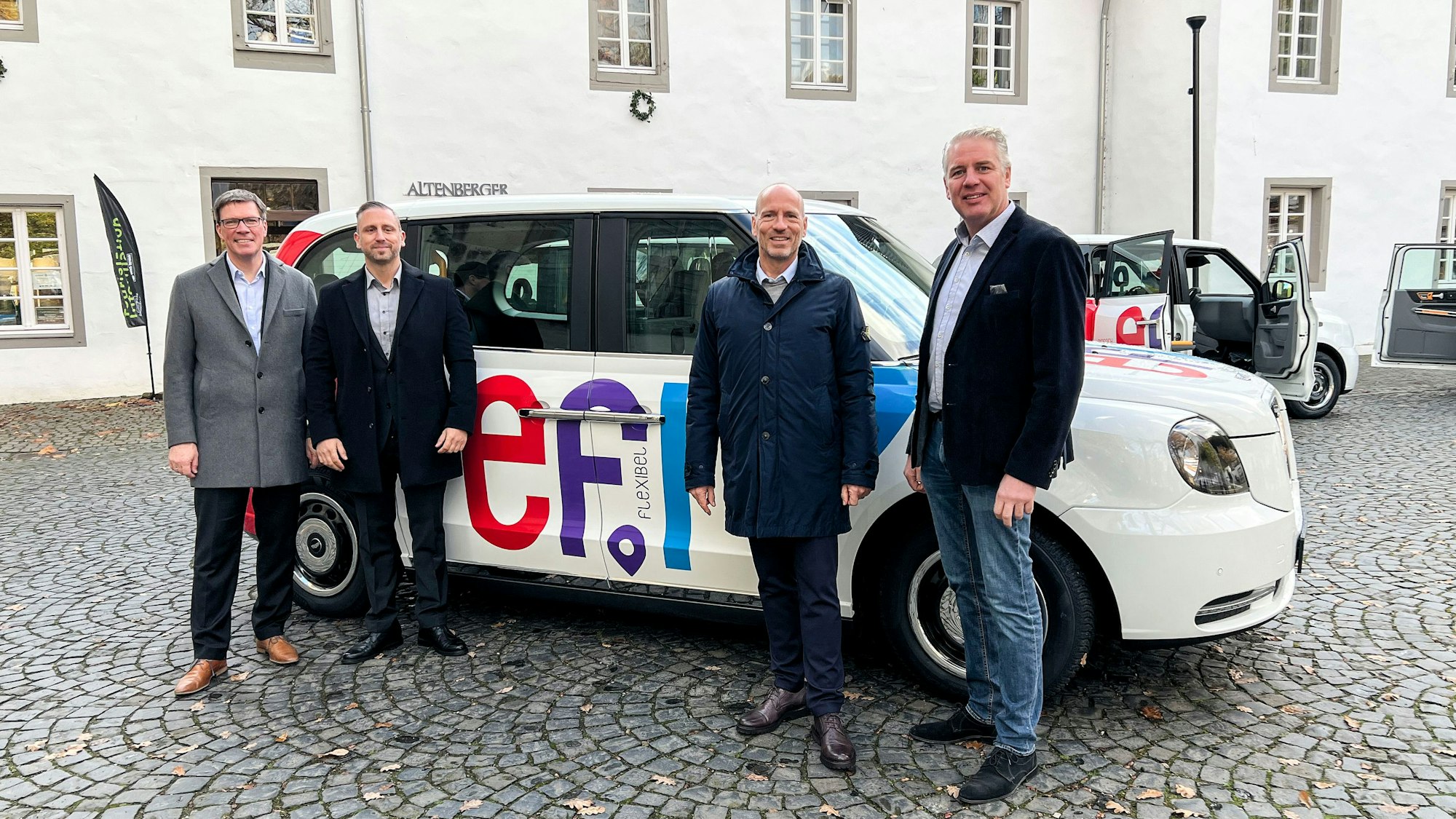 Landrat Stephan Santelmann, Georg Königsmann vom Unternehmen Clevershuttle, Wupsi-Chef Marc Kretkowski und Bürgermeister Robert Lennerts stehen an einem der neuen Efi-Großraumtaxis.
