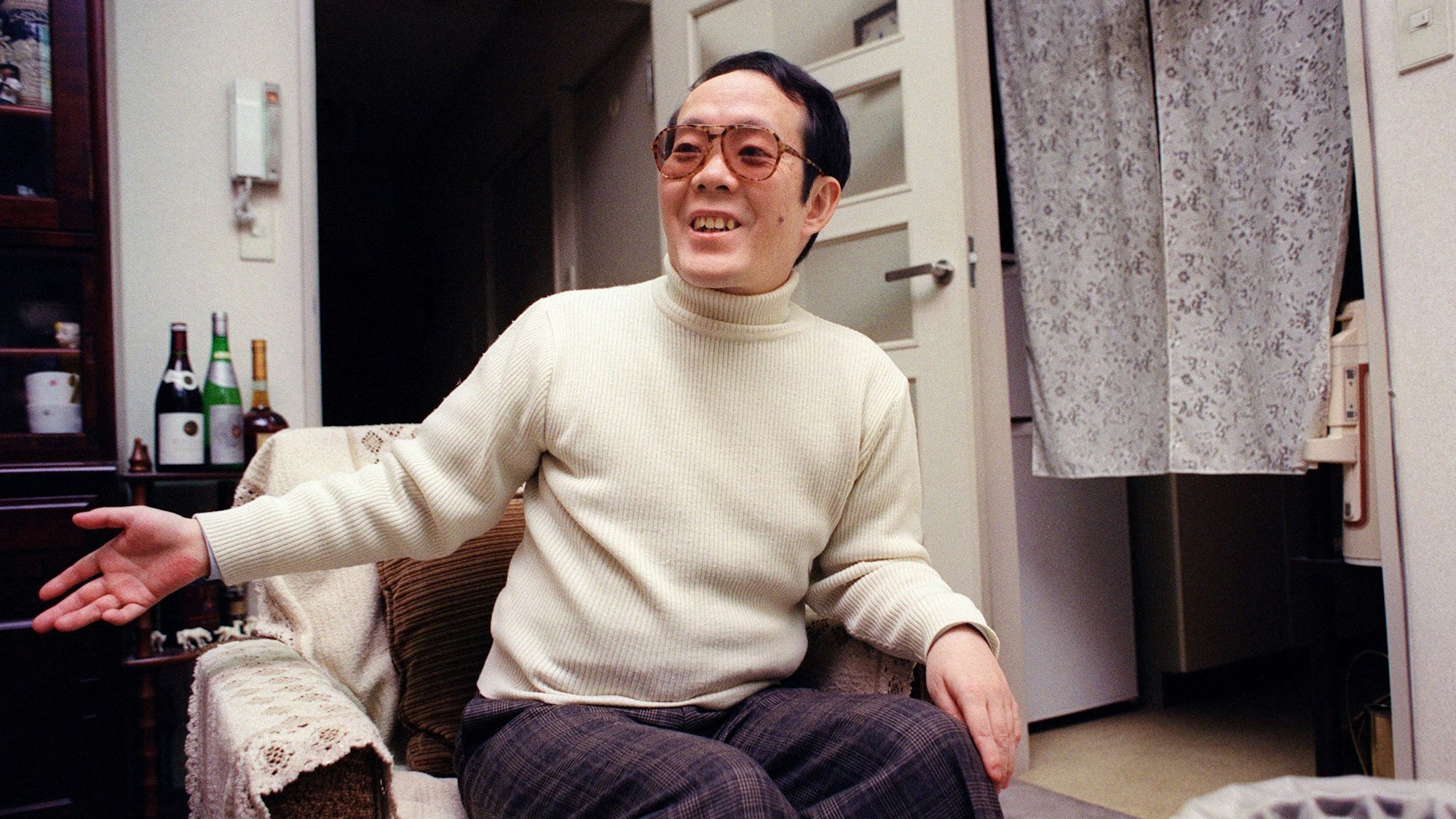 Issei Sagawa gestikuliert auf einem Sessel.
