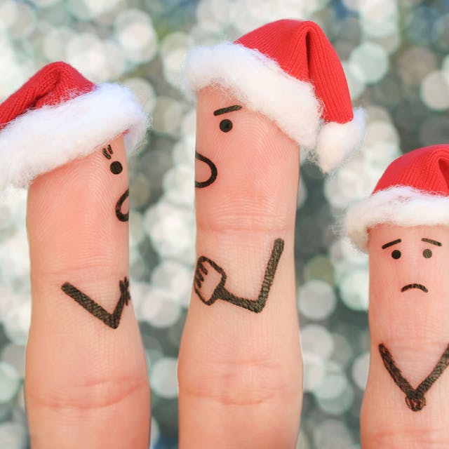 Finger mit Weihnachtsmannmützen und aufgemalten Gesichtern als streitendes Paar mit weinendem Kind.