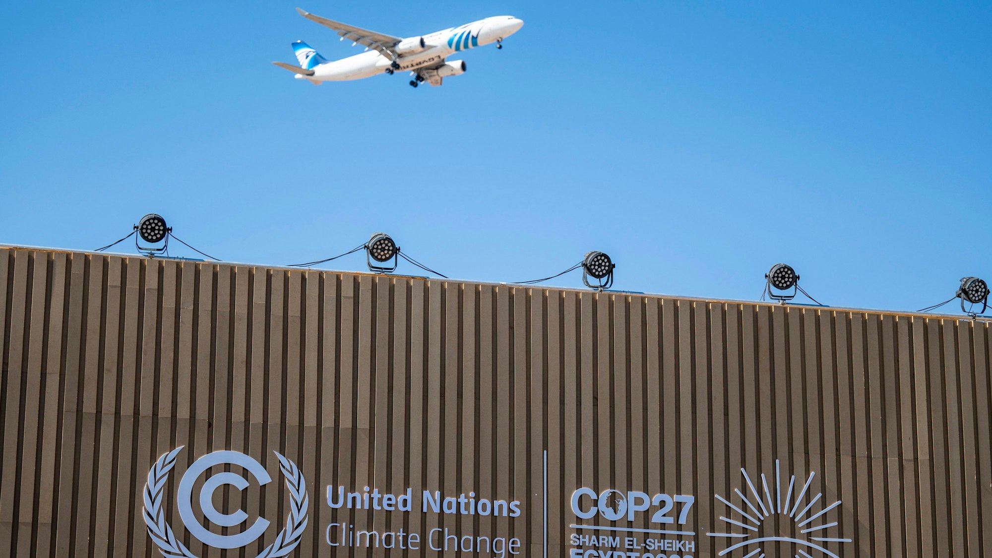 Ein Flugzeug fliegt beim UN-Klimagipfel COP27 über einen Konferenzraum mit dem Logo der COP27.