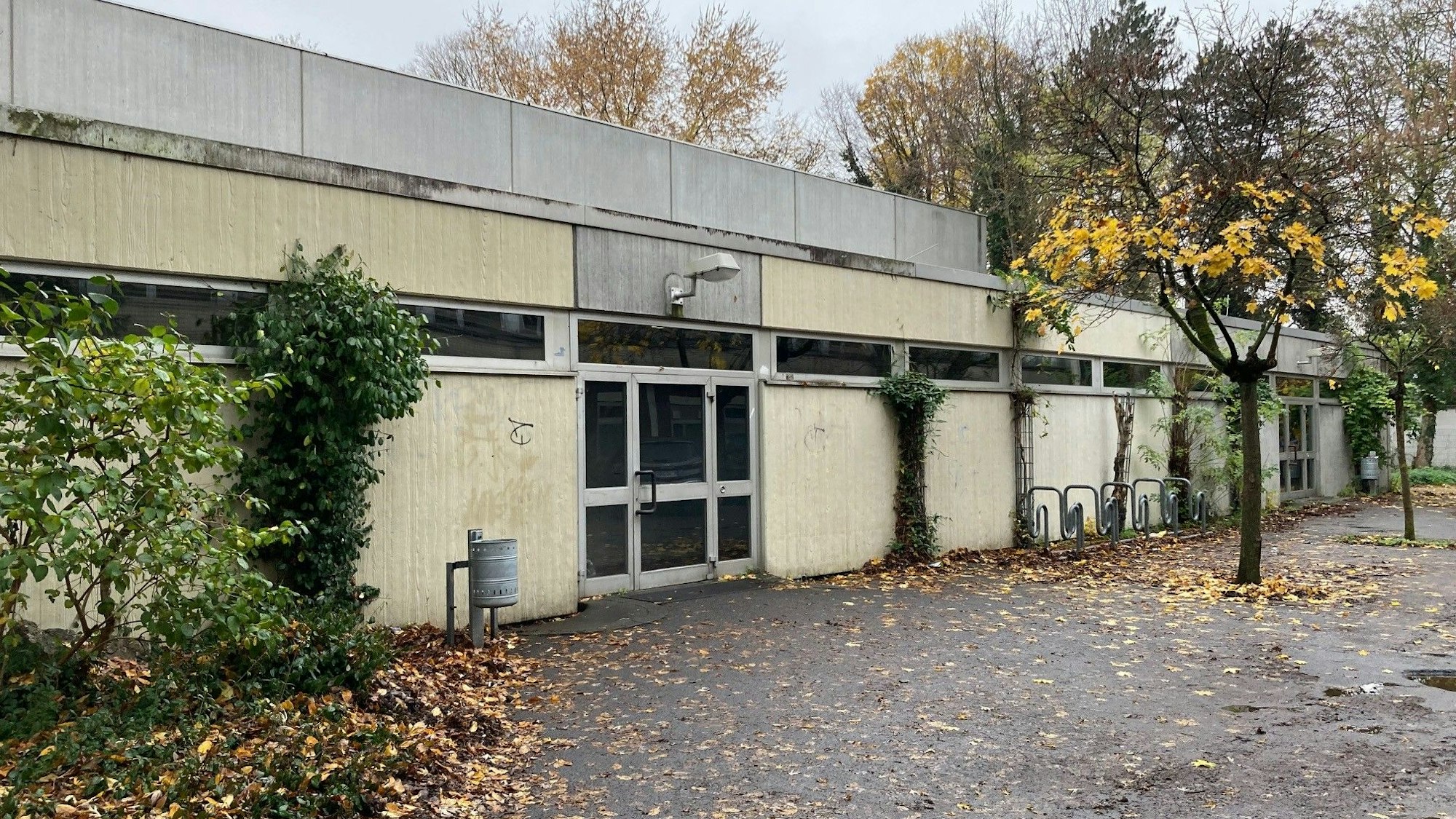 Der Eingang der Sporthalle Zum Kuckental in Frechen. Ein graues Gebäude mit einem Flachdach und einer grauen Tür mit Glasscheiben.