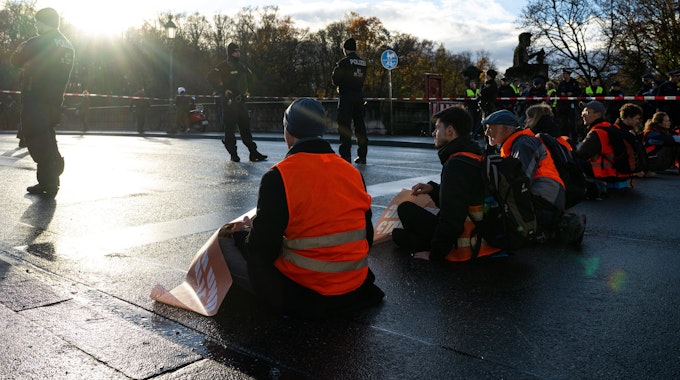In einer Reihe sitzen Klimaaktivisten der Umweltschutzbewegung „Letzte Generation“ sitzen auf der Münchner Prinzregentenstraße und blockieren den Verkehr.