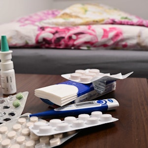 Ein Fieberthermometer und Medikamente liegen auf einem Nachttisch (gestellte Szene). Mit der kalten Jahreszeit nehmen auch die Infektionen mit Influenza wieder zu.