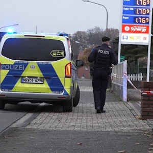 Ein Polizeifahrzeug steht vor einer Tankstelle in Lengerich, daneben steht ein Polizist.