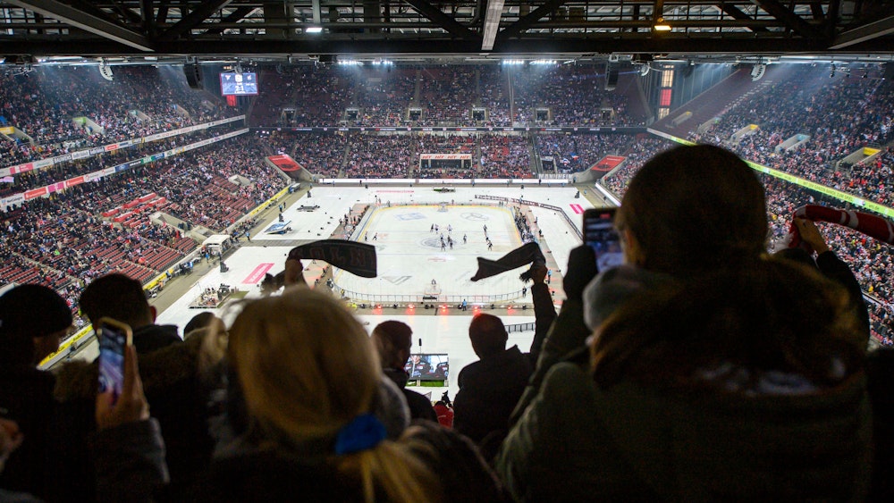 Fans schwenken beim Winter Game der Kölner Haie gegen die Adler Mannheim Schals auf der Tribüne.
