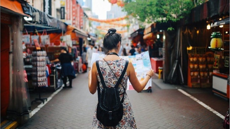 Eine junge Frau liest während einer Reise eine Landkarte.