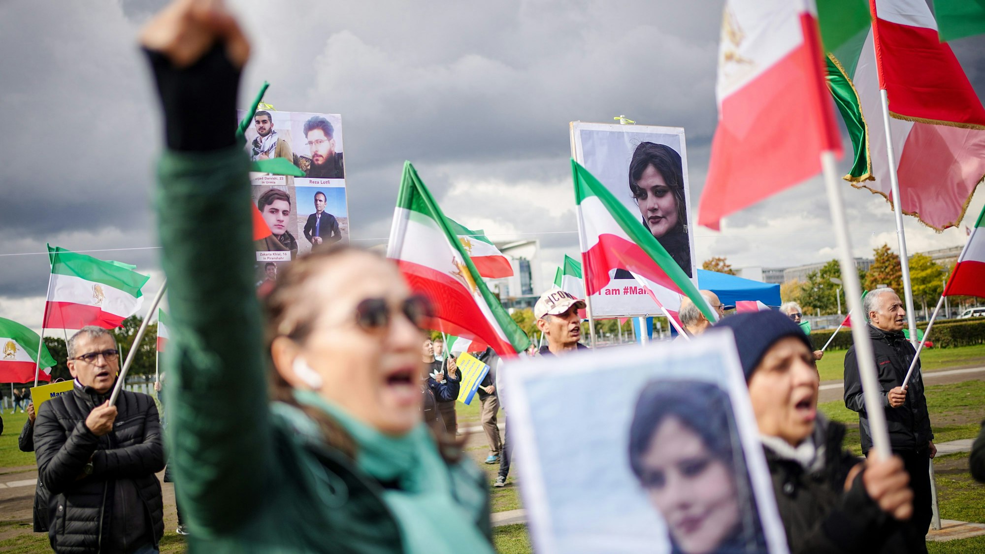 Mit Plakaten von Masha Amini demonstrieren Teilnehmer für Demokratie und Freiheit im Iran auf der Reichstagswiese in Berlin.