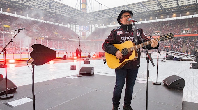 Björn Heuser spielt Gitarre auf der Eisfläche im Stadion in Müngersdorf.