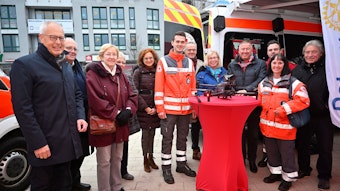 Vertreter von Deutschem Roten Kreuz und des Rotary Clubs Overath-Rösrath/Bergisches Land stehen um einen Tisch mit einer Drohne.