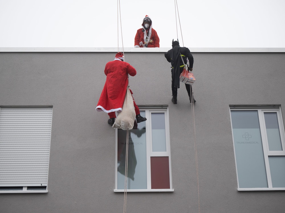 Höhenretter, die als Nikolaus und Batman verkleidet sind, seilen sich am Kinderhaus Nesthäkchen ab und übergeben Geschenke.