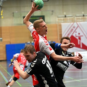 En Handballspieler setzt sich gegen seinen Gegner durch und wirft aufs Tor.