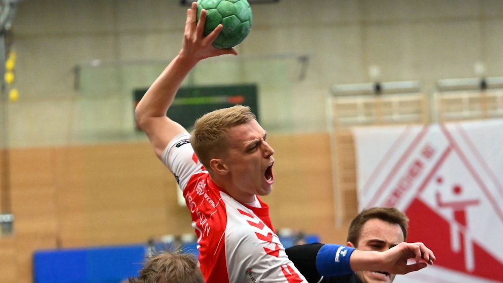 En Handballspieler setzt sich gegen seinen Gegner durch und wirft aufs Tor.