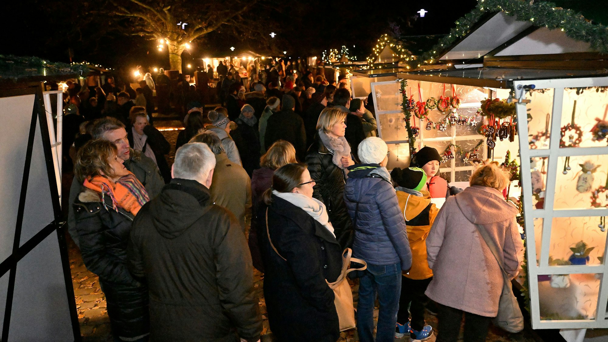 Besucher drängen sich im Abenddunkel an den Ständen des Adventsmarkt in Altenberg.