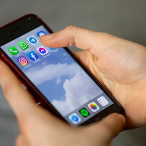 Auf dem Bildschirm eines Smartphones, das eine Person in der Hand hält, sieht man die Symbole verschiedener sozialer Medien und Messenger-Dienste.&nbsp;