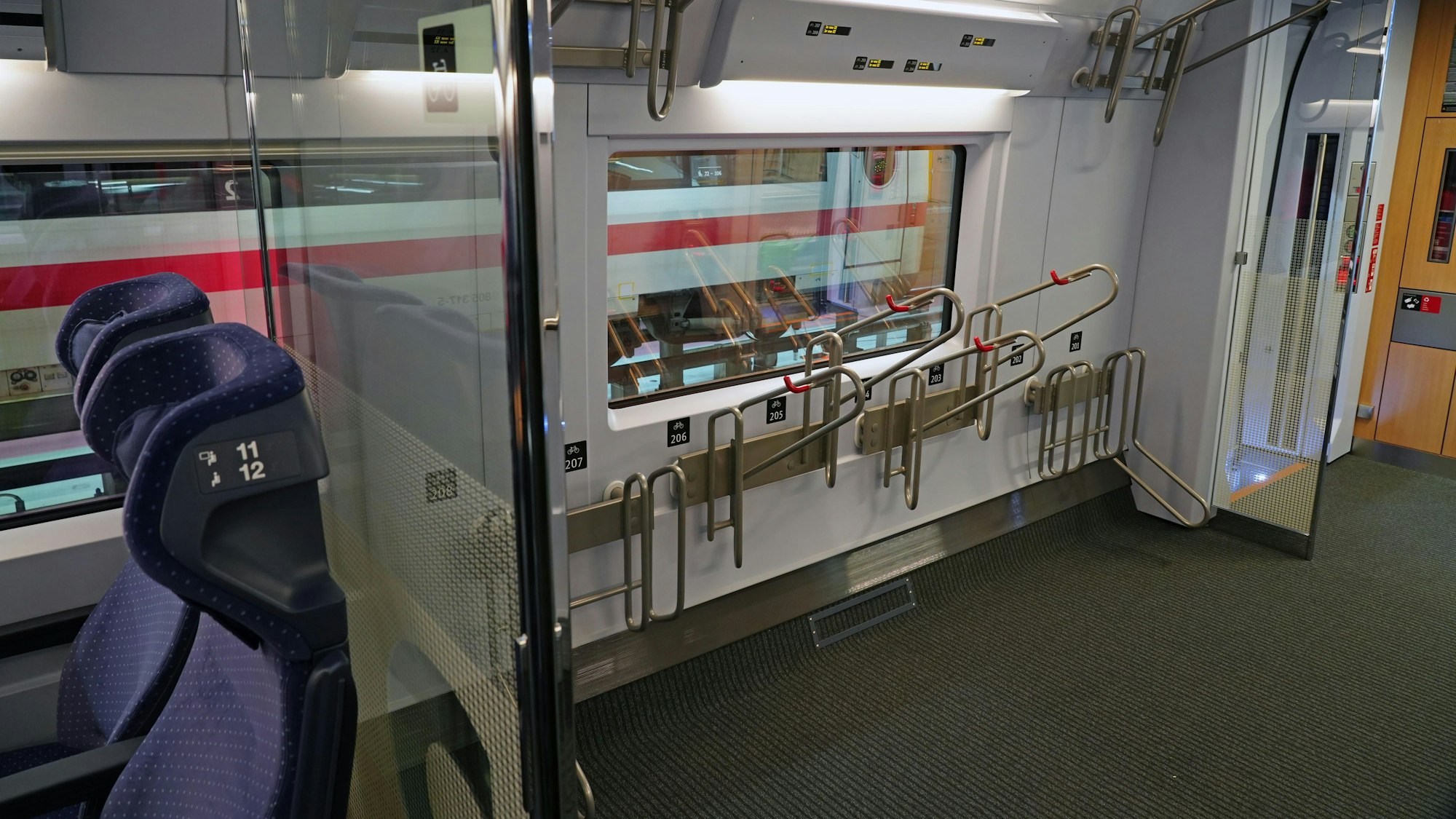 Die neuen Fahrradständer in einem Abteil eines ICE 3neo der Deutschen Bahn. Außerdem sind blaue Sitze zu sehen.