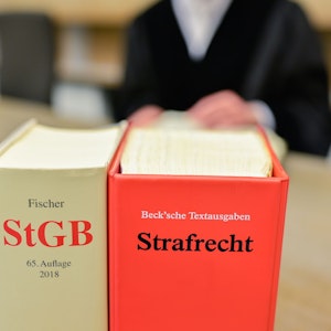 Ein Richter sitzt in einem Sitzungssaal des Landgerichts an der Richterbank hinter Büchern mit der Aufschrift „StGB“ und „Strafrecht“.