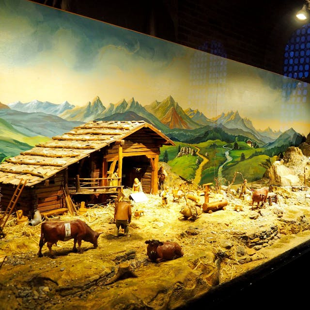Eine Krippen-Landschaft mit Stall, gemaltem Berg-Panorama im Hintergrnd, Kühen und Menschen ist zu sehen.