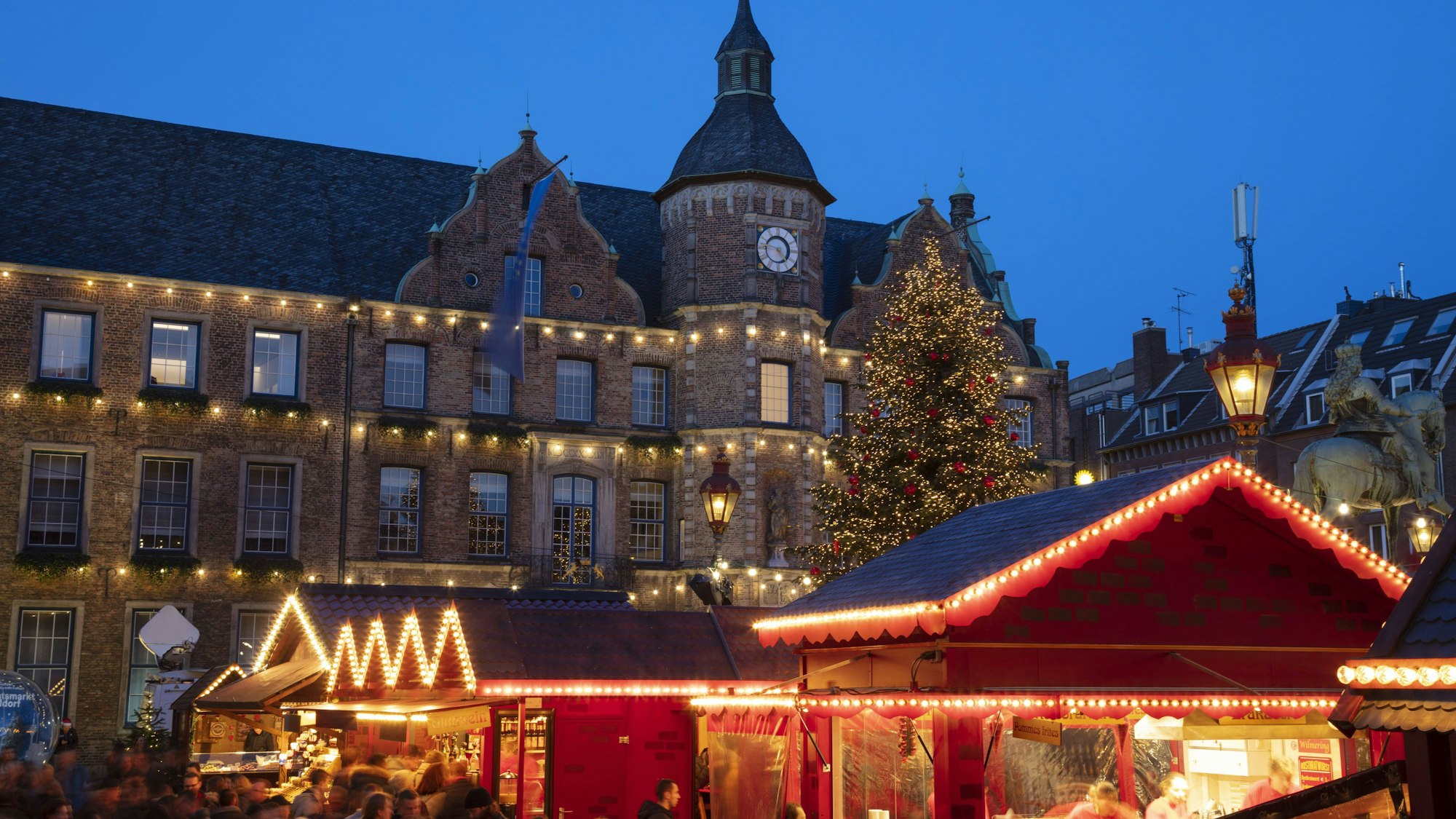 Weihnachtsmarkt-Stände vor dem Rathaus in Düsseldorf. Im Hintergrund steht ein Weihnachtsbaum.