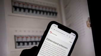 Eine Webseite der Rhein-Energie zur Erfassung des Zählerstands ist vor einem geöffneten Sicherungskasten zu sehen.