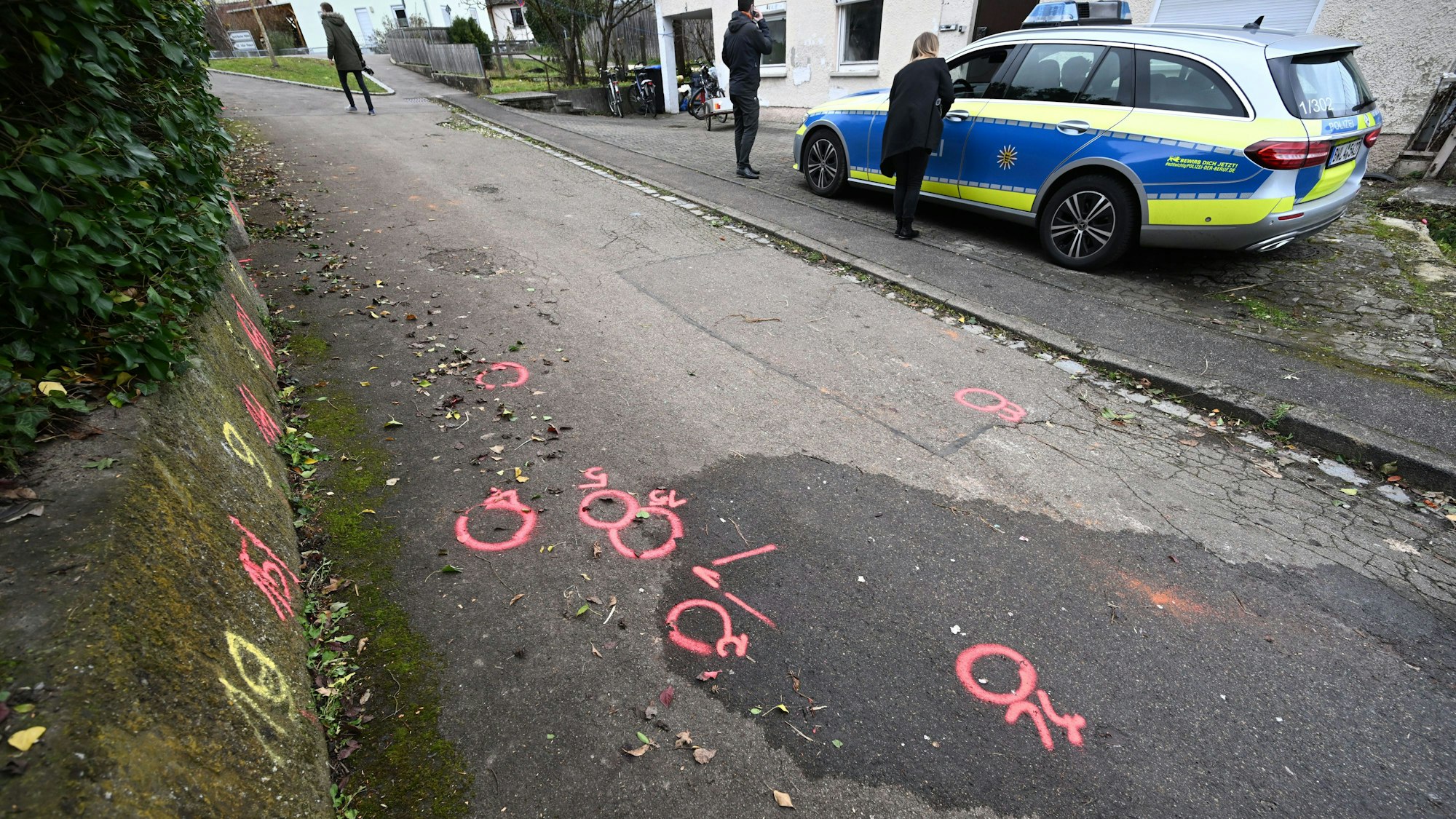 Markierungen der Spurensicherung der Polizei sind an einem Tatort auf einem Weg angebracht.