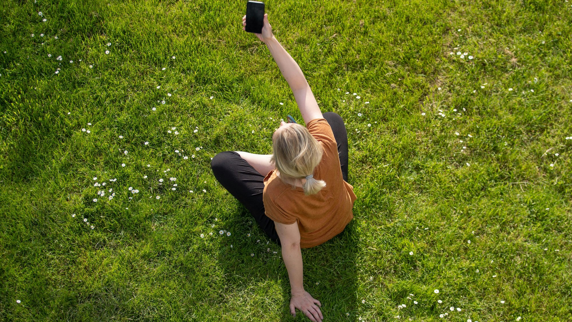 Eine Frau hält ein Smartphone in der Hand und macht ein Selfie.