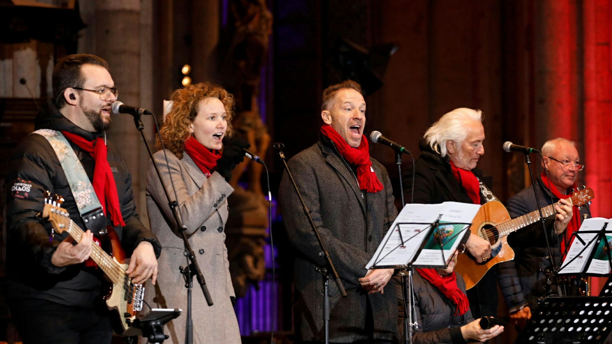 Die Höhner und Sängerin Nicola stehen singend im Kölner Dom.