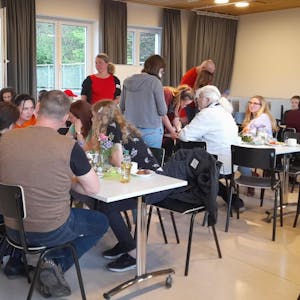 Café International des Fluchtpunkts Kürten: An mehreren längeren Tischen sitzen Menschen verschiedener Nationen und unterhalten sich.