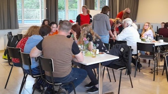 Café International des Fluchtpunkts Kürten: An mehreren längeren Tischen sitzen Menschen verschiedener Nationen und unterhalten sich.