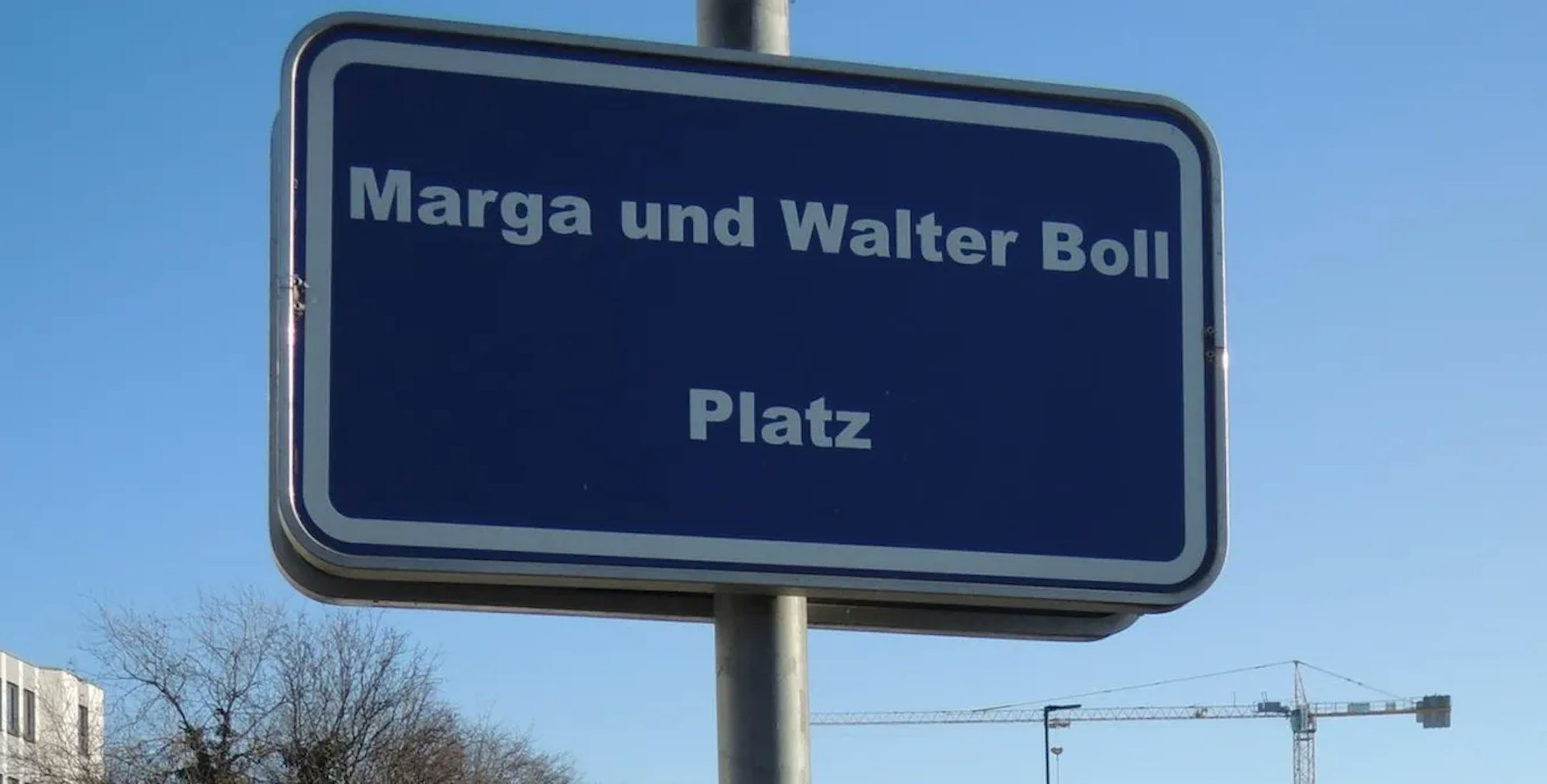 Weiße Schrift auf einem blauen Schild weist auf den Marga-und-Walter-Boll-Platz in Kerpen hin.