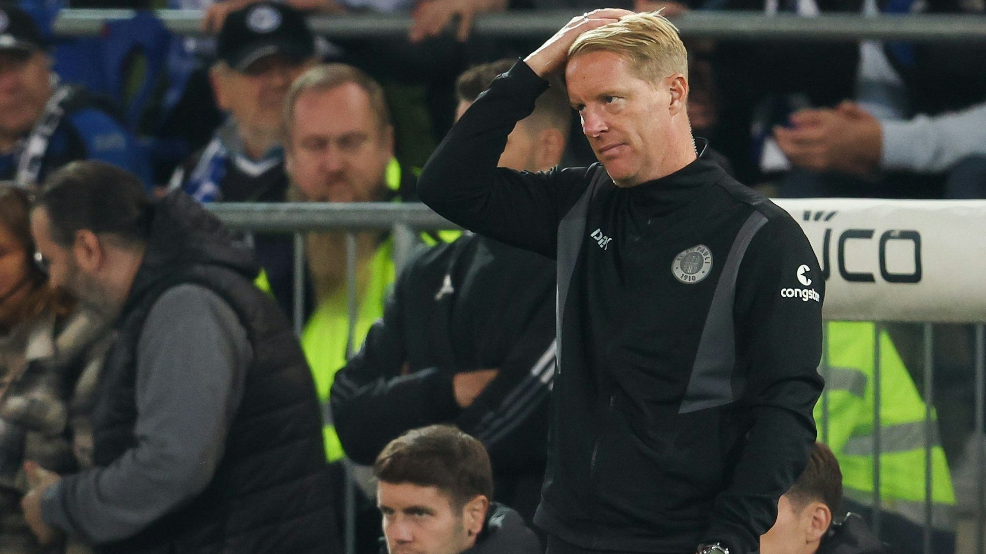 Timo Schultz zeigt sich bei einem Spiel des FC St. Pauli enttäuscht und fährt sich nachdenklich durchs Haar.