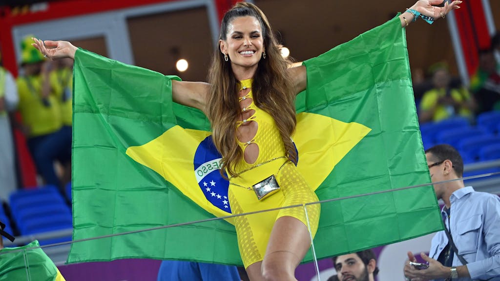 Izabel Goulart trägt ein gelbes Outfit und eine Brasilien-Flagge.