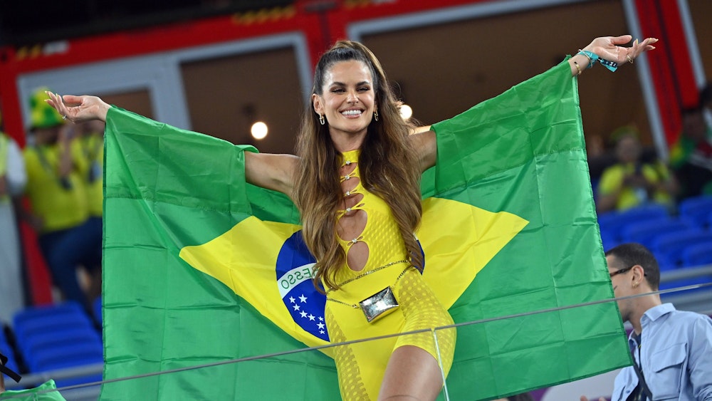 Izabel Goulart trägt ein gelbes Outfit und eine Brasilien-Flagge.