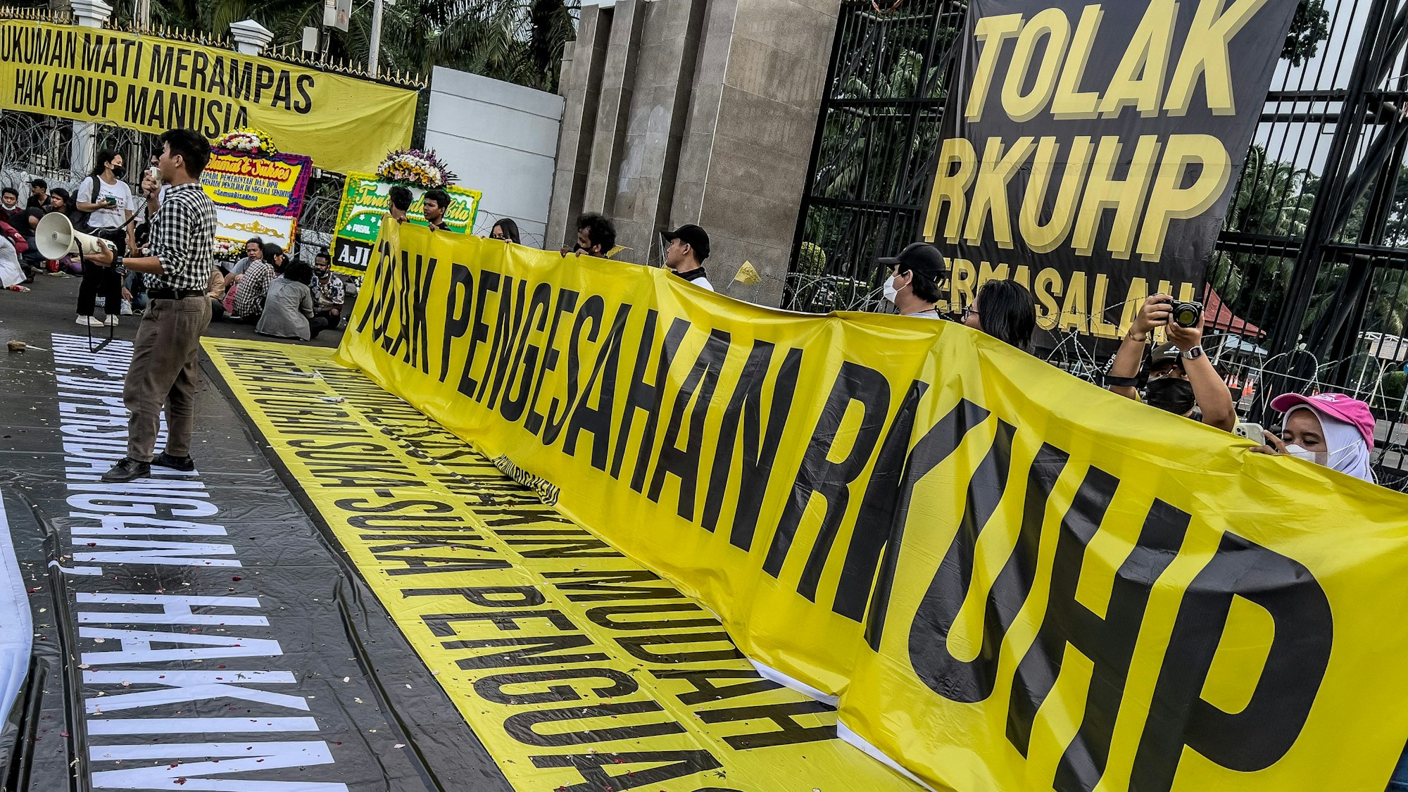 Das Foto zeigt eine indonesische Protestaktion mit gelb-schwarzen Bannern und vielen Menschen.