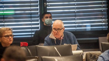 Das Ratsmitglied Erhard Schoofs sitzt im Leverkusener Ratssaal. An seinem rechten Ohr baumelt eine FFP2-Maske.