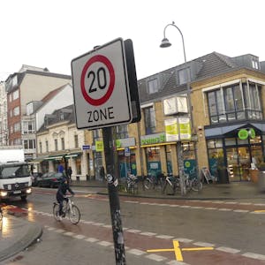Ein Radfahrer fährt an einem Hinweisschilder auf Tempo 20 an einer Zufahrtsstraße der Venloer Straße vorbei.
