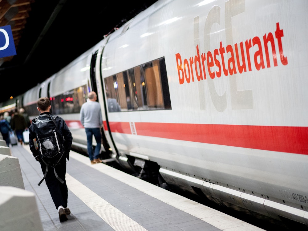 Fahrgäste gehen am frühen Morgen mit ihrem Gepäck über einen Bahnsteig am Hauptbahnhof, um in einen ICE der Deutschen Bahn einzusteigen.