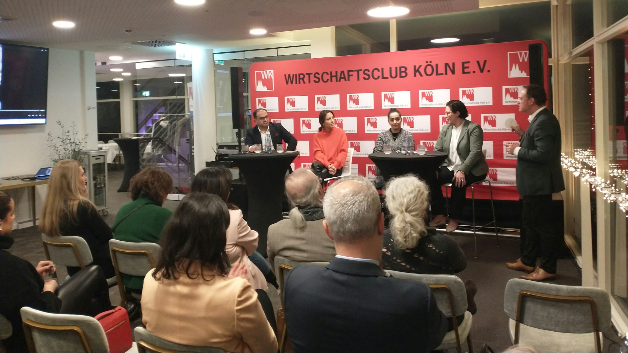 Kölner Wirtschaftsclub mit 4 Podiumsgästen und Moderator, im Vordergrund Publikum.