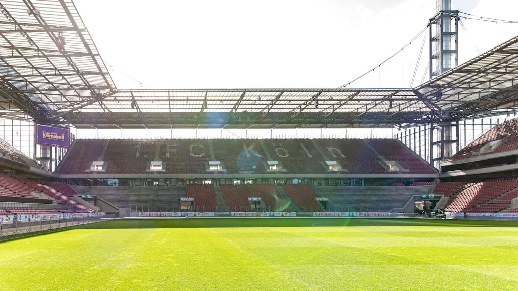 Innenansicht des RheinEnergie-Stadions in. Die Zuschauerplätze sind leer, die Sonne scheint.