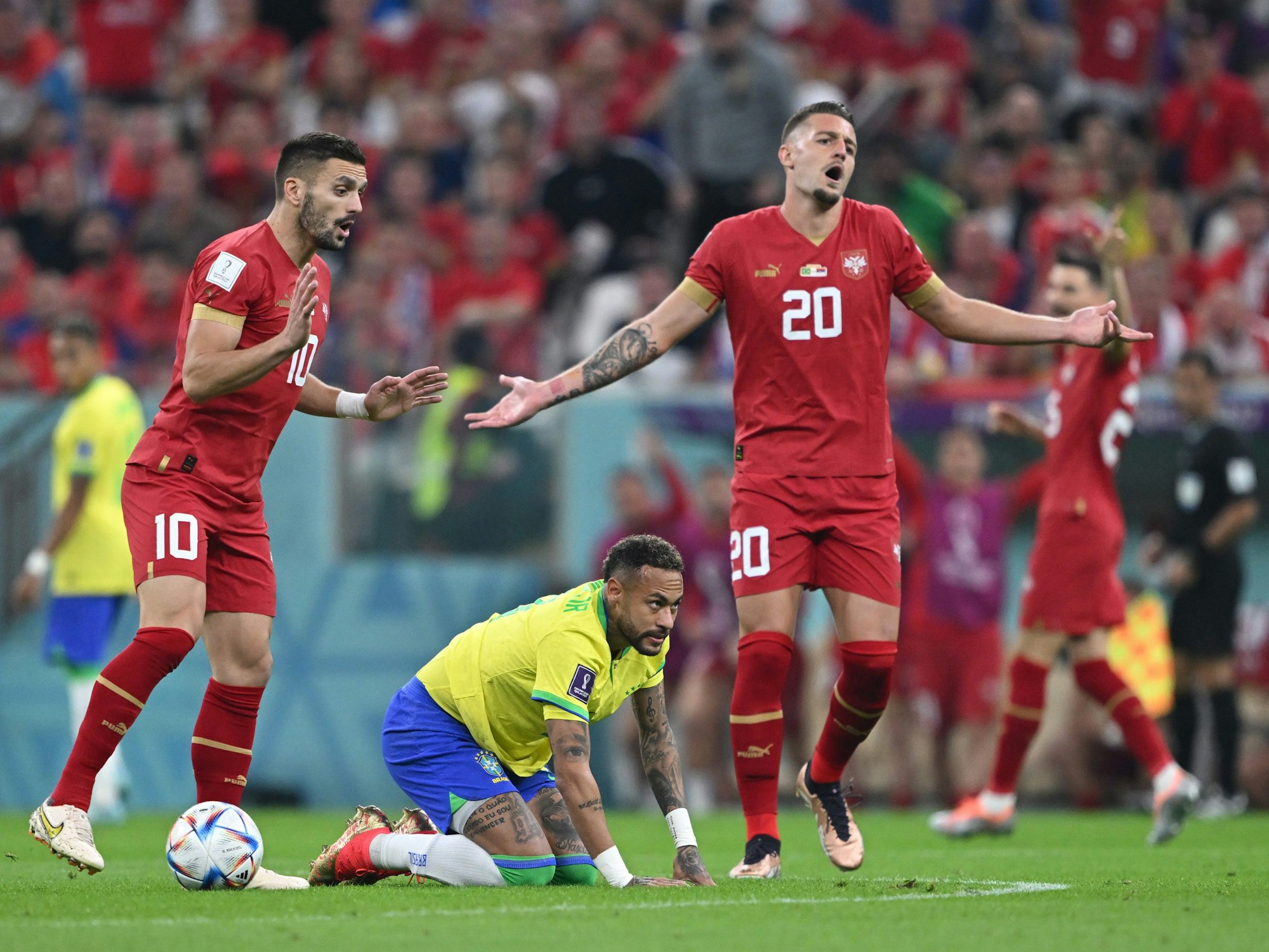 Dusan Tadic (l.) und Sergej Milinkovic-Savic (r.) reklamieren, Brasilien-Star Neymar kniet dazwischen auf dem Rasen im WM-Gruppenspiel Serbiens am 24. November 2022 gegen die Selecao.