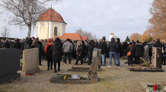 Eine große Gruppe Menschen steht auf einem Firedhof, im Hintergrund eine Kriche, und trauern um das getötete Mädchen bei dessen Beisetzung auf dem Friedhof in Illerkirchberg.