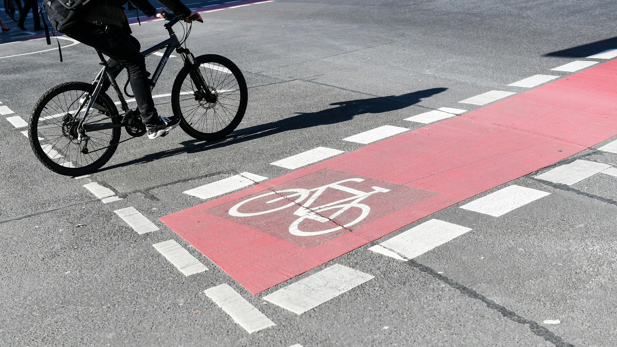 Ein Radfahrer fährt auf einer Straße neben einer rot markierten Radweg.