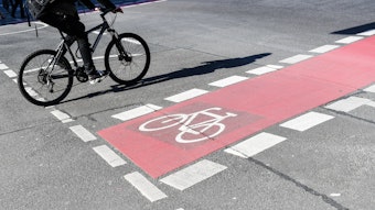 Ein Radfahrer fährt auf einer Straße neben einer rot markierten Radweg.