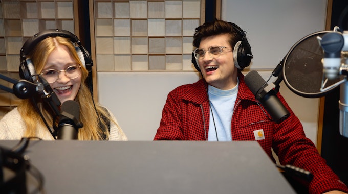 Carolin Worbs und Miguel Robitzky sitzen mit Kopfhörern und Mikrofonen in den Produktionsräumen des ZDF Magazin Royale in Ehrenfeld, wo sie ihren Podcast "too many tabs" aufnehmen.