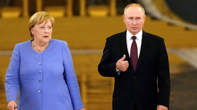 Altkanzlerin Angela Merkel (CDU) steht neben dem russischen Präsidenten Wladimir Putin, beide tragen formale Kleidung und blicken ernst.