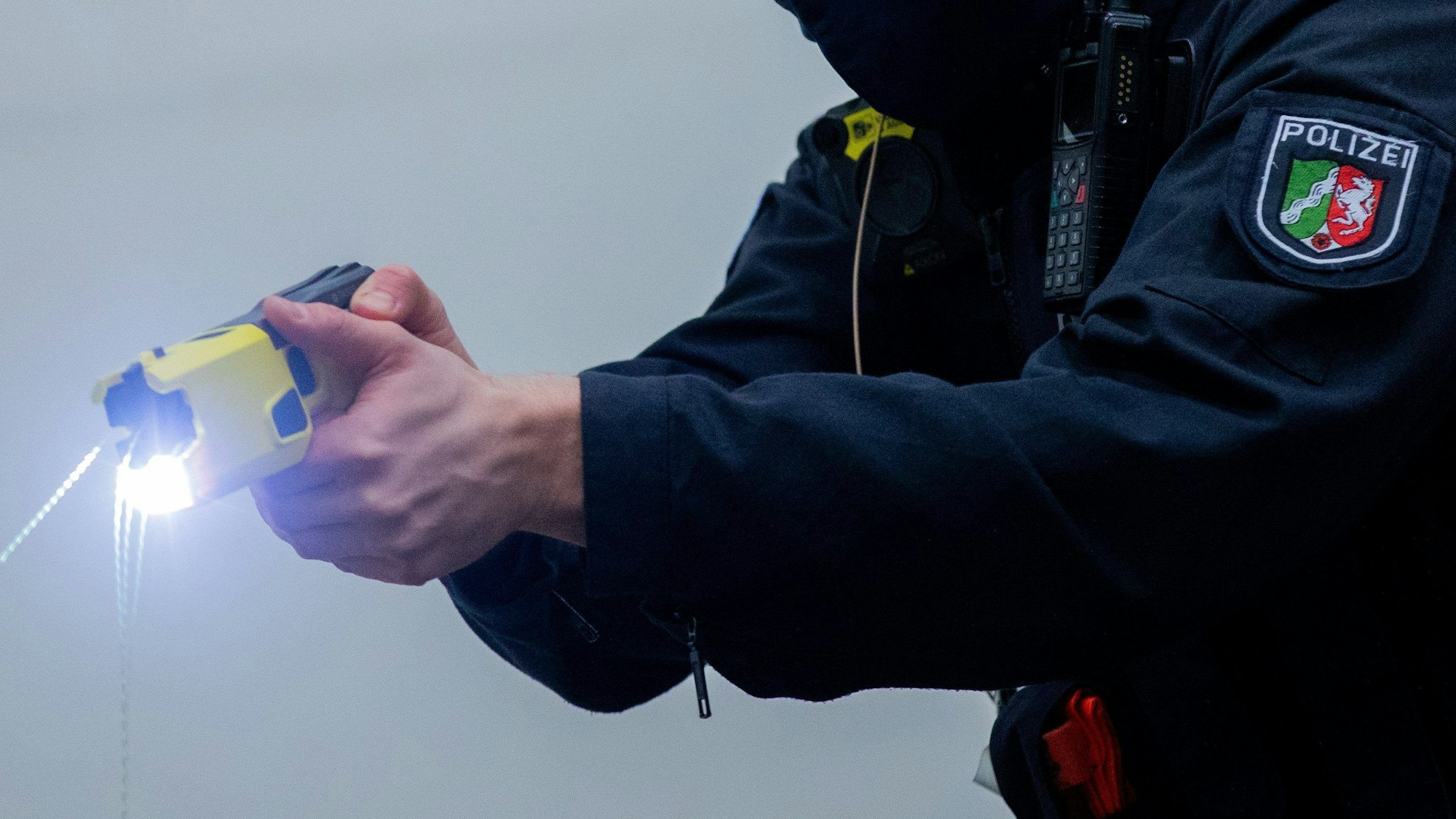 Das Bild zeigt einen Polizeibeamten, der einen Taser in der Hand hält.