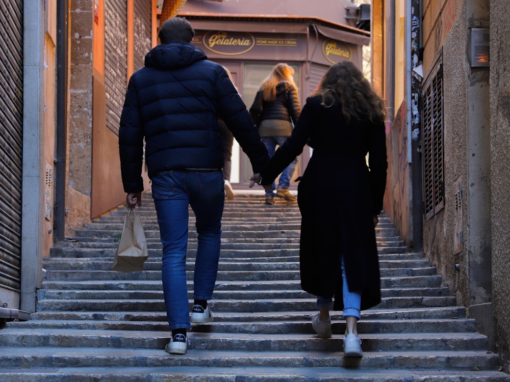 Ein Paar geht an geschlossenen Läden in der Innenstadt von Palma de Mallorca vorbei.
