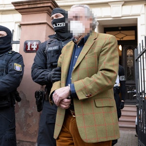 Bei einer Razzia gegen sogenannte „Reichsbürger“ führen vermummte Polizisten, nach der Durchsuchung eines Hauses Heinrich XIII P. R. zu einem Polizeifahrzeug.