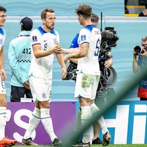 Harry Maguire (l.) und John Stones (r.) jubeln mit Englands Torschütze Harry Kane nach dessen 2:0 im WM-Achtelfinale von Katar gegen den Senegal.